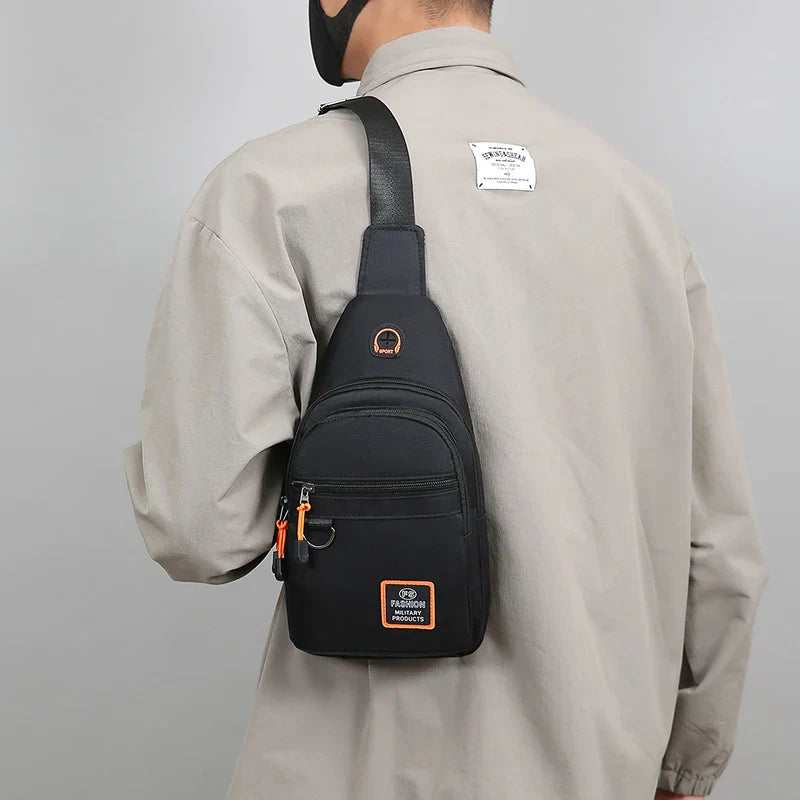 Man wearing a compact black crossbody sling bag on the back, featuring multiple storage compartments and an adjustable shoulder strap for comfortable everyday use.
